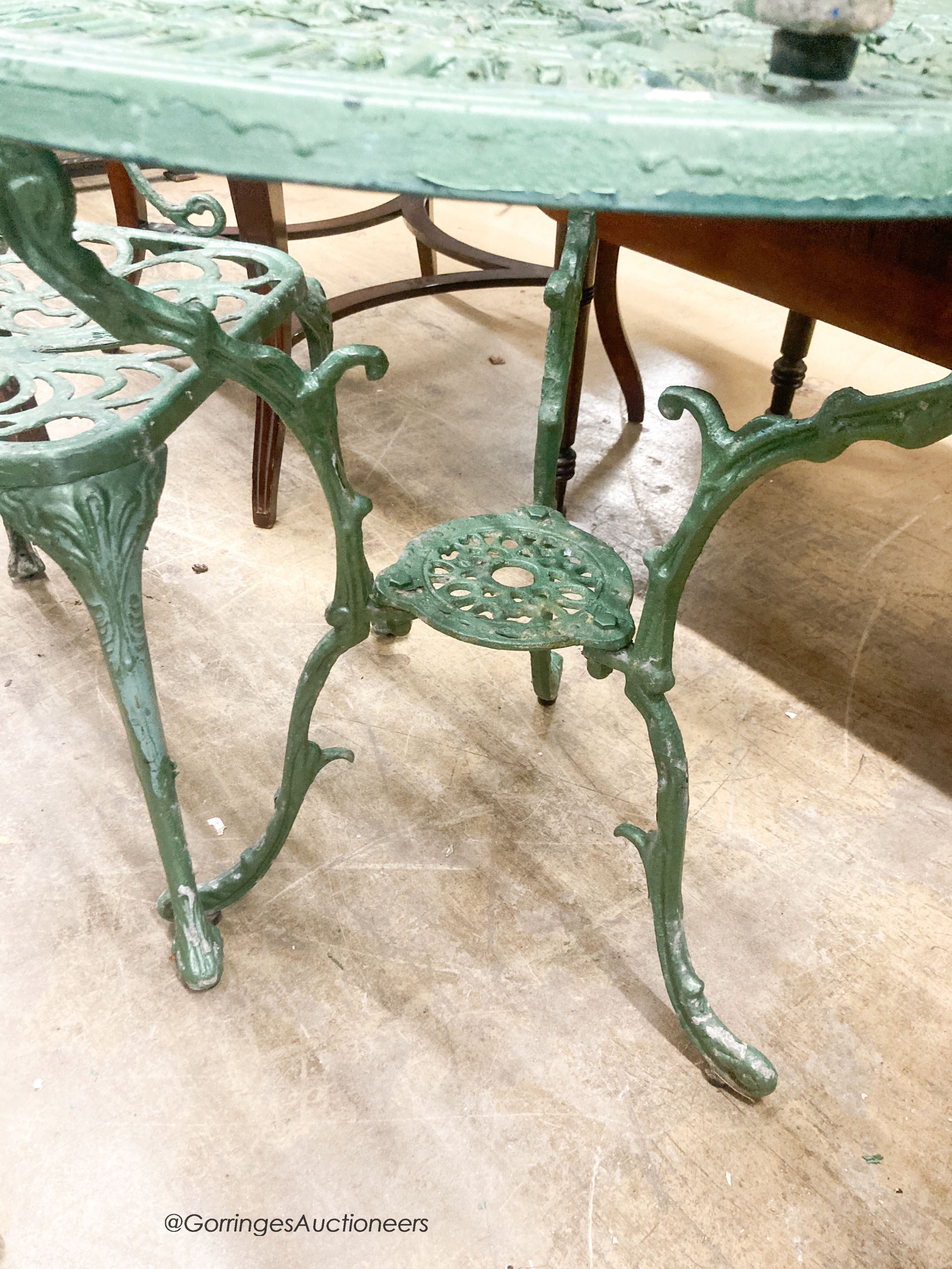 A cast painted aluminium circular garden table, diameter 69cm together with three similar elbow chairs